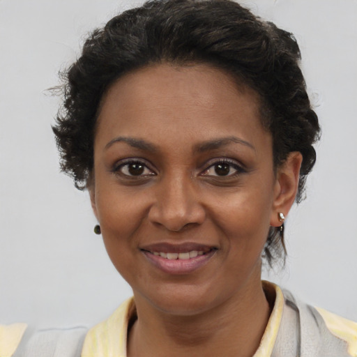 Joyful black young-adult female with short  brown hair and brown eyes