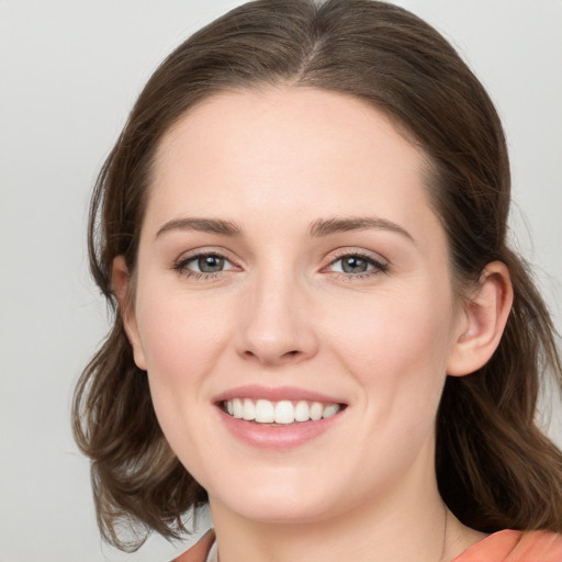 Joyful white young-adult female with medium  brown hair and grey eyes