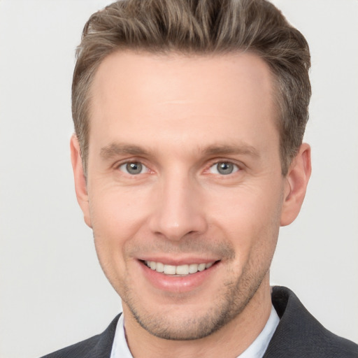 Joyful white young-adult male with short  brown hair and grey eyes