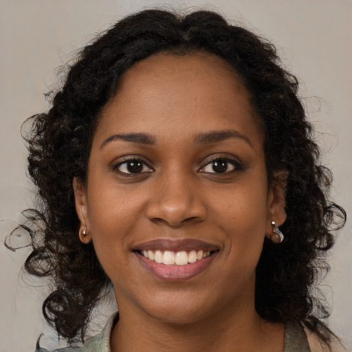 Joyful black young-adult female with long  brown hair and brown eyes