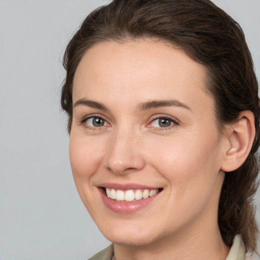 Joyful white young-adult female with medium  brown hair and grey eyes