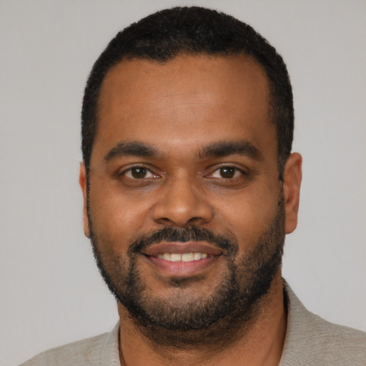 Joyful black young-adult male with short  black hair and brown eyes