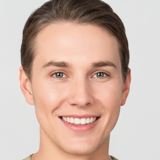 Joyful white young-adult male with short  brown hair and grey eyes