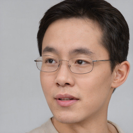 Joyful asian young-adult male with short  brown hair and brown eyes