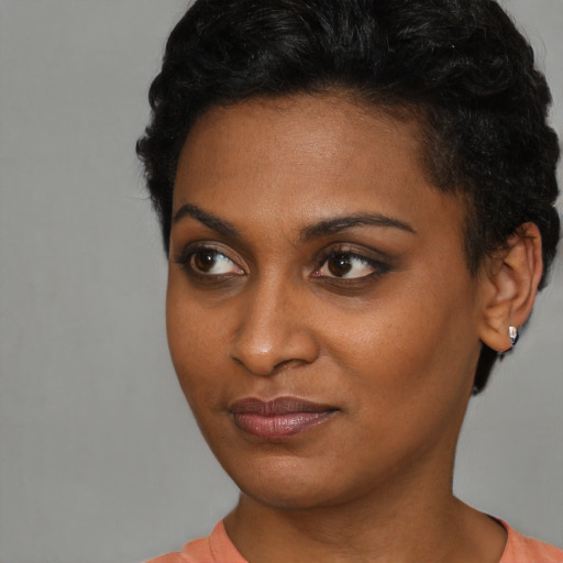 Joyful black young-adult female with short  black hair and brown eyes