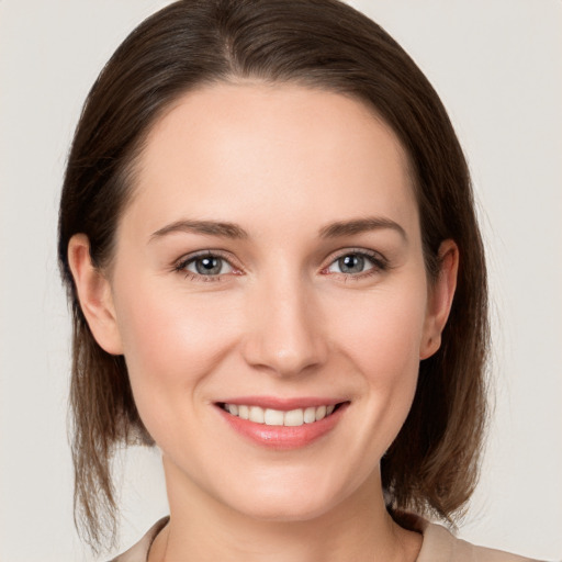 Joyful white young-adult female with medium  brown hair and grey eyes