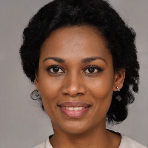 Joyful black young-adult female with short  black hair and brown eyes