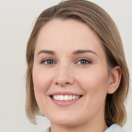 Joyful white young-adult female with medium  brown hair and grey eyes