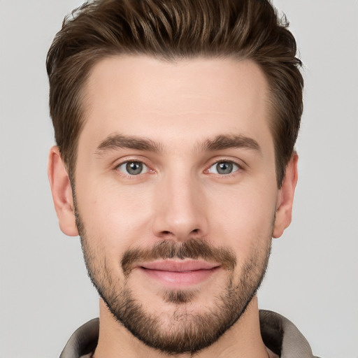 Joyful white young-adult male with short  brown hair and grey eyes