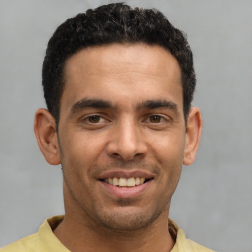 Joyful latino young-adult male with short  brown hair and brown eyes