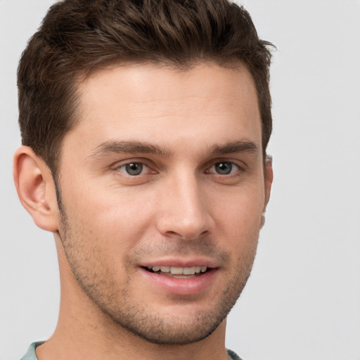 Joyful white young-adult male with short  brown hair and grey eyes