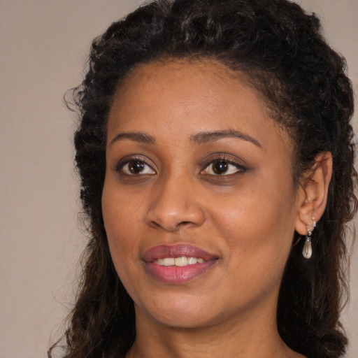 Joyful black young-adult female with long  brown hair and brown eyes