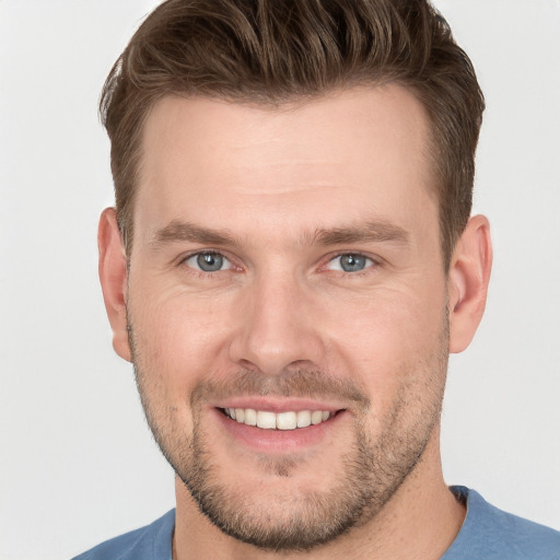 Joyful white young-adult male with short  brown hair and grey eyes