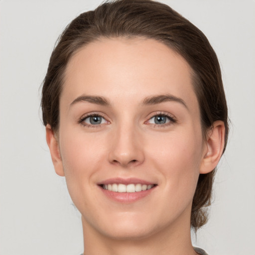 Joyful white young-adult female with medium  brown hair and grey eyes