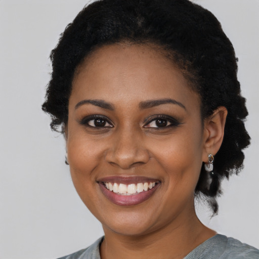 Joyful black young-adult female with short  black hair and brown eyes