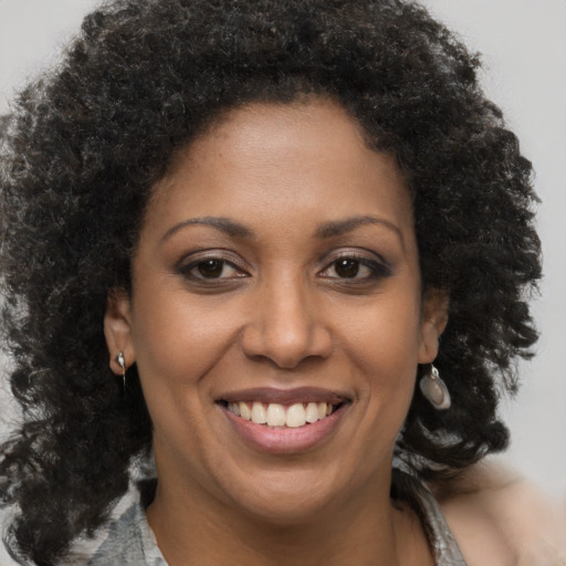 Joyful black young-adult female with long  brown hair and brown eyes