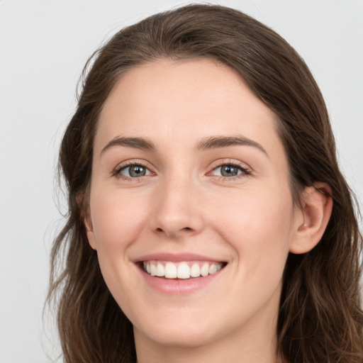 Joyful white young-adult female with long  brown hair and grey eyes