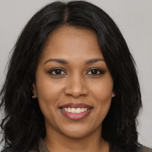 Joyful black young-adult female with long  black hair and brown eyes