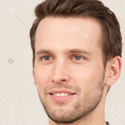 Joyful white young-adult male with short  brown hair and grey eyes