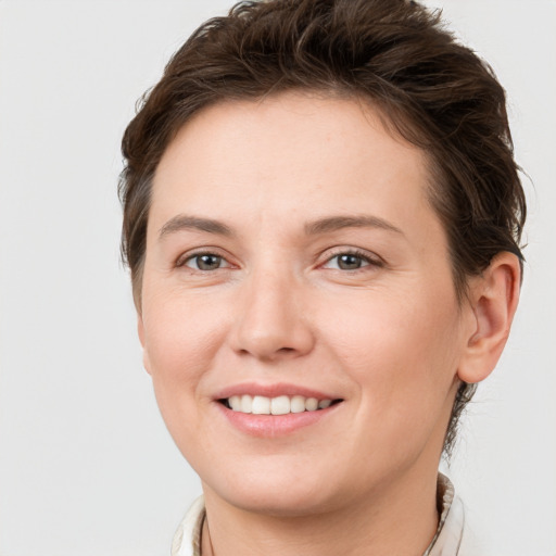 Joyful white young-adult female with short  brown hair and grey eyes