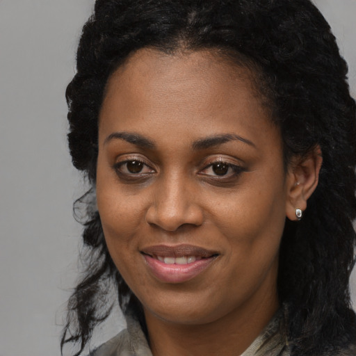 Joyful black young-adult female with long  brown hair and brown eyes