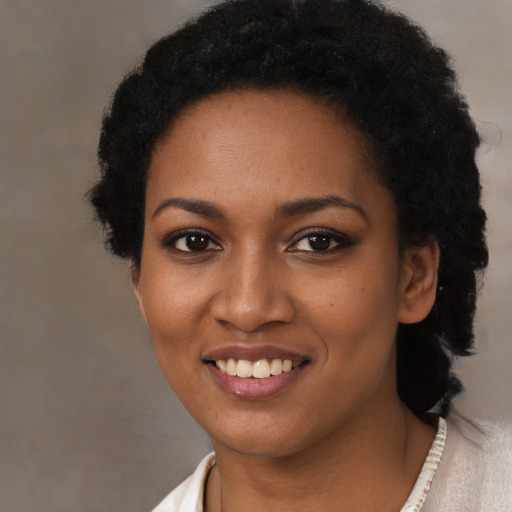 Joyful black young-adult female with short  black hair and brown eyes