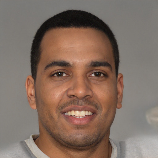 Joyful black young-adult male with short  brown hair and brown eyes