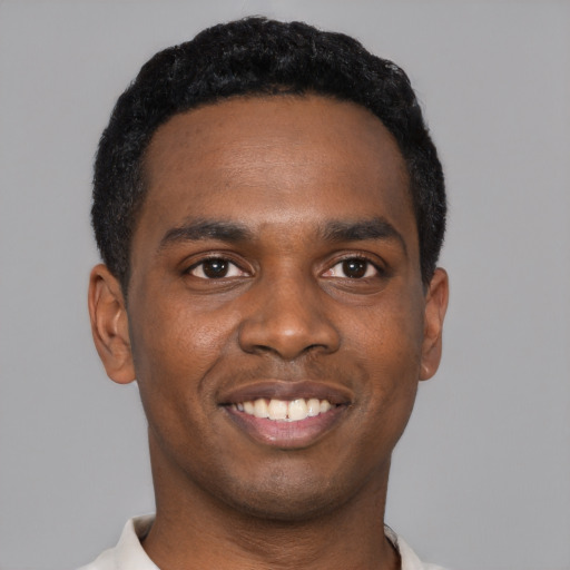 Joyful black young-adult male with short  black hair and brown eyes