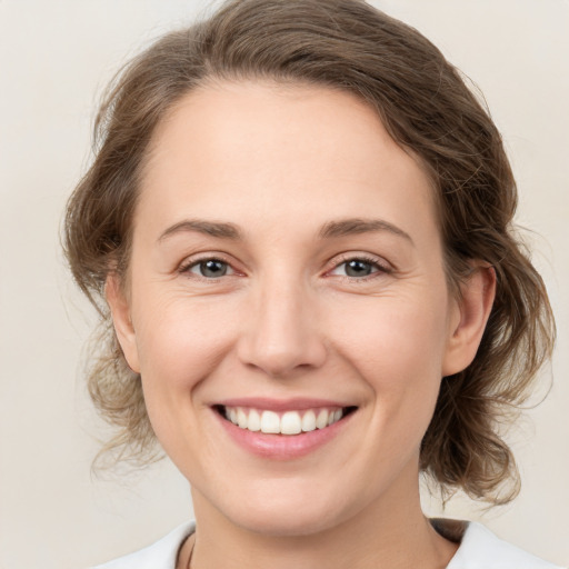 Joyful white young-adult female with medium  brown hair and grey eyes