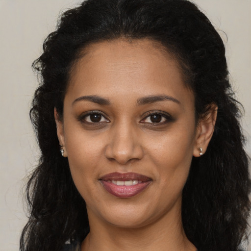 Joyful black young-adult female with long  brown hair and brown eyes