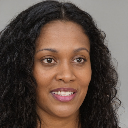 Joyful black young-adult female with long  brown hair and brown eyes