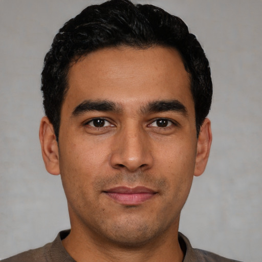 Joyful latino young-adult male with short  black hair and brown eyes