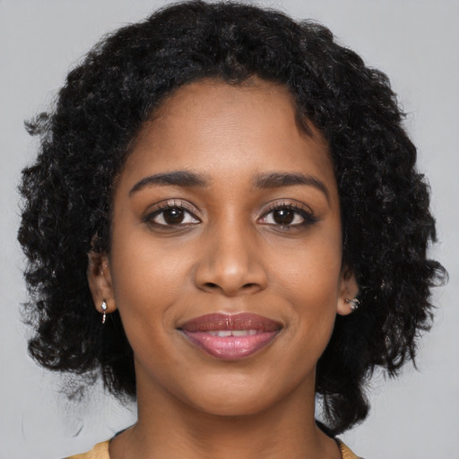 Joyful black young-adult female with long  black hair and brown eyes