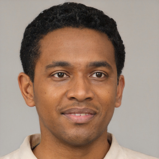 Joyful black young-adult male with short  black hair and brown eyes