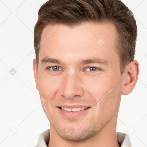 Joyful white young-adult male with short  brown hair and grey eyes