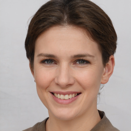 Joyful white young-adult female with short  brown hair and grey eyes