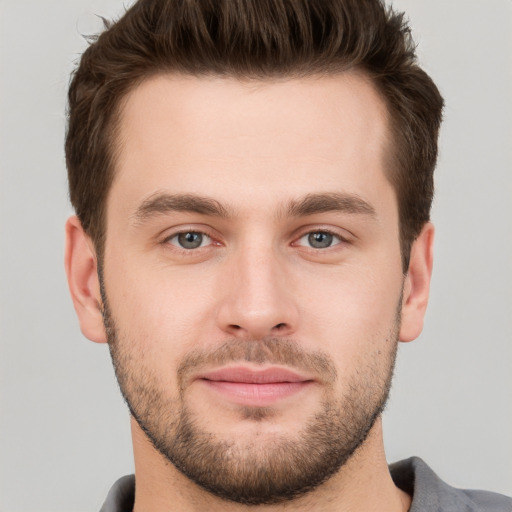 Joyful white young-adult male with short  brown hair and grey eyes