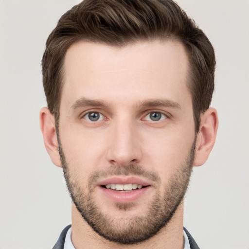 Joyful white young-adult male with short  brown hair and grey eyes