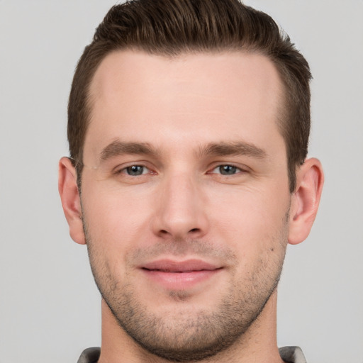 Joyful white young-adult male with short  brown hair and grey eyes