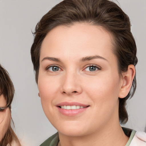 Joyful white young-adult female with medium  brown hair and grey eyes