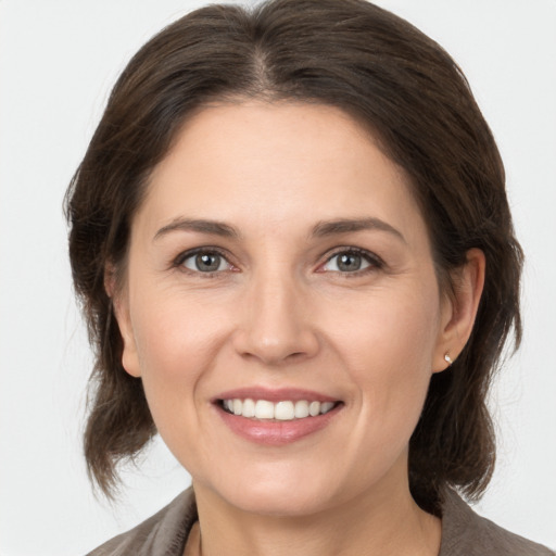 Joyful white young-adult female with medium  brown hair and grey eyes