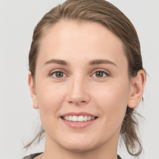 Joyful white young-adult female with medium  brown hair and grey eyes