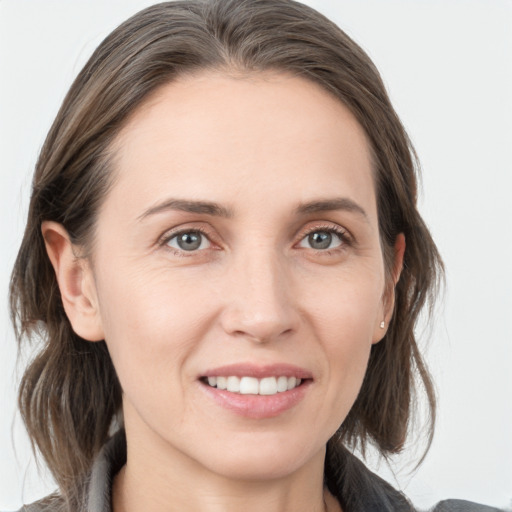 Joyful white young-adult female with medium  brown hair and grey eyes