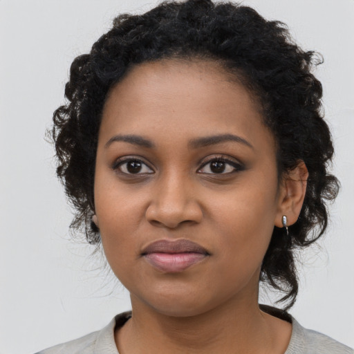 Joyful black young-adult female with long  black hair and brown eyes
