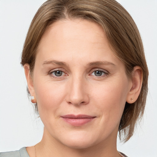 Joyful white young-adult female with medium  brown hair and grey eyes