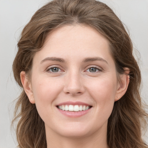 Joyful white young-adult female with long  brown hair and grey eyes