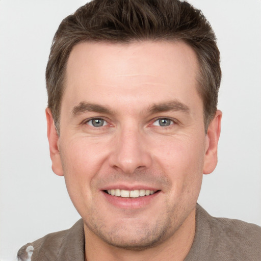 Joyful white young-adult male with short  brown hair and grey eyes