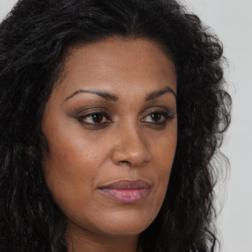 Joyful black young-adult female with long  brown hair and brown eyes