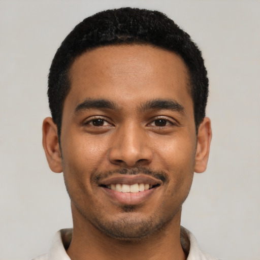 Joyful black young-adult male with short  black hair and brown eyes