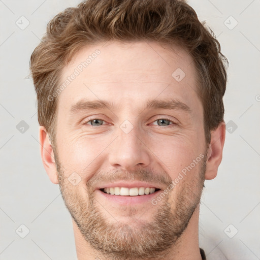 Joyful white young-adult male with short  brown hair and grey eyes